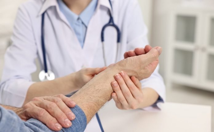 Doctor examining patient wrist 696x429